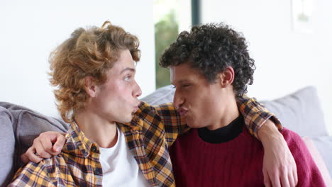 Happy-diverse-gay-male-couple-embracing-on-sofa-at-home,-slow-motion