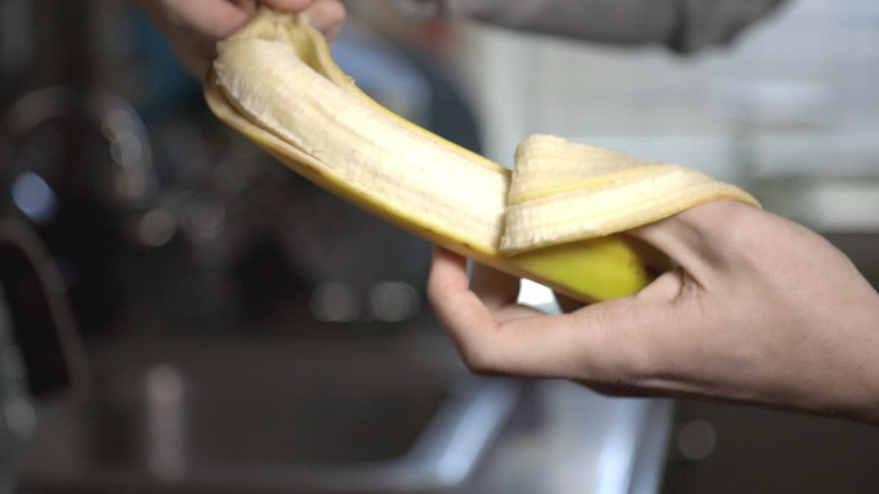 Hands Peeling A Ripe And Yellow Banana. - close up shot