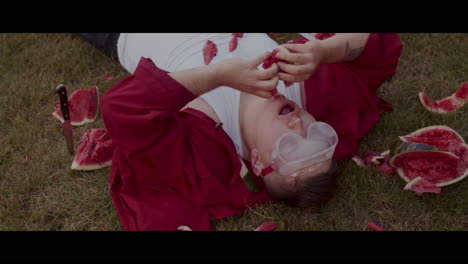 man eating watermelon in grass