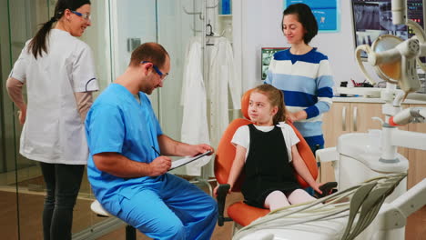 Nurse-taking-notes-on-clipboard-about-little-girl-dental-problems