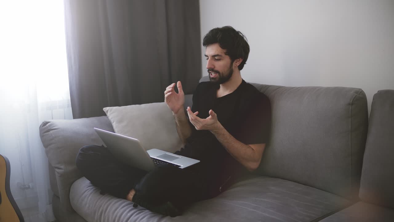Man sitting on sofa and making a video call, gesturing