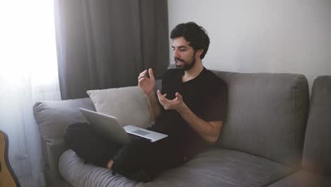 Hombre-Sentado-En-El-Sofá-Y-Haciendo-Una-Videollamada,-Gesticulando