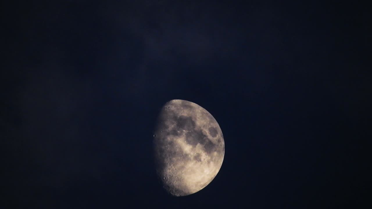 Moon at night with cloud real time. 4k video moon in the black sky.  Clouds passing by moon at night. night sky with cloudy weather