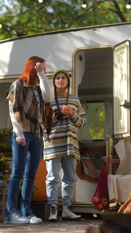 two women talking outdoors by a camper van