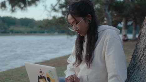 asian girl surfing the internet on laptop in the park