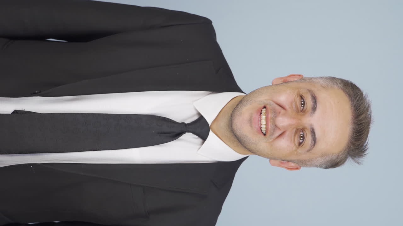 카메라를 향해 손을 흔드는 사업가의 수직 비디오.