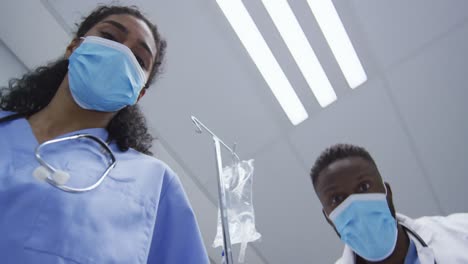 diverse female and male doctors wearing face mask transporting patient