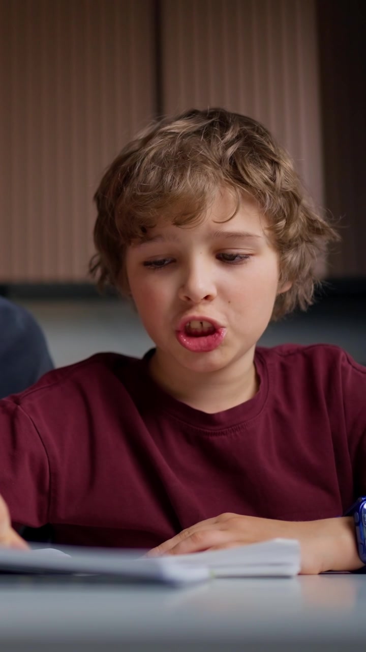 Giovane ragazzo che parla e indica mentre studia.