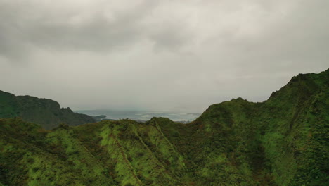 Revealing-Shot-Of-The-Island-Of-Oahu-Behind-Lush-Rocky-Mountain-In-Hawaii---aerial-drone