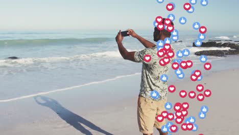 animazione di icone dei social media su un uomo afroamericano che si fa un selfie sulla spiaggia