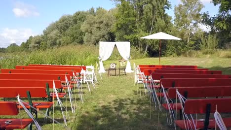 gran vuelo aéreo de drones de un paseo nupcial de una boda gratis frente a asientos vacíos en la naturaleza junto al lago en verano