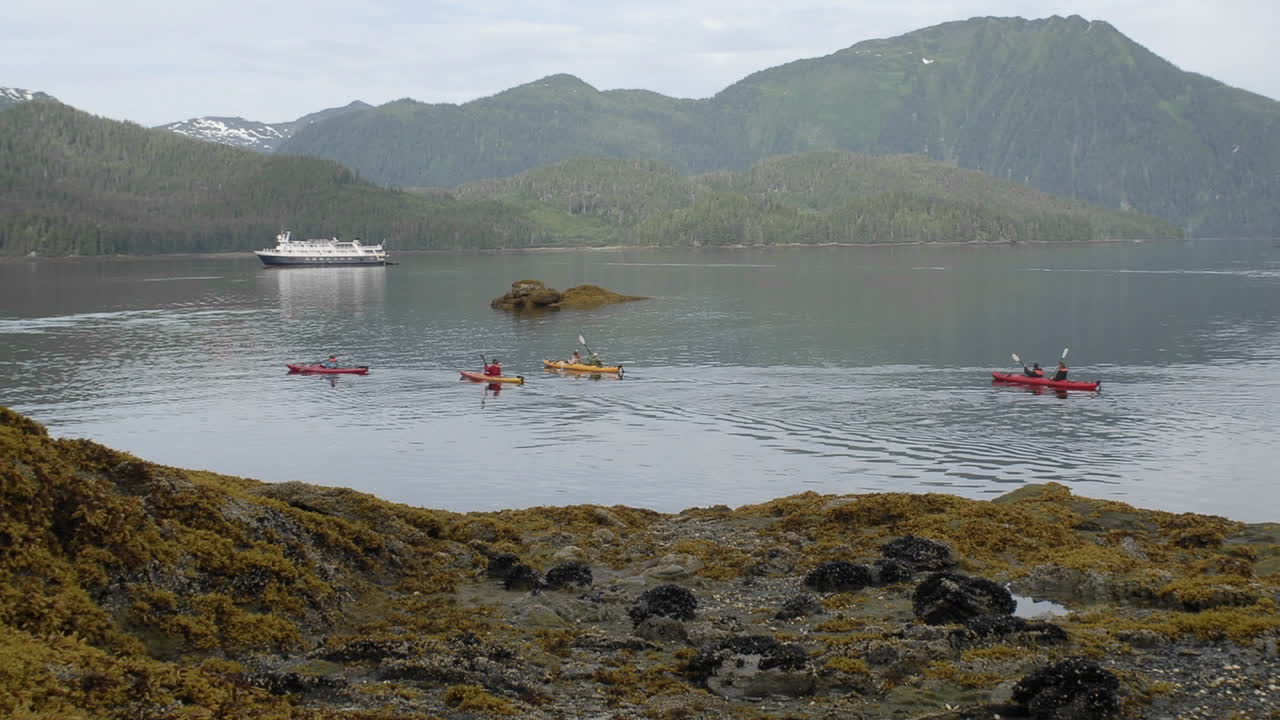 lapso de tiempo de kayakistas de marea entrante y barco anclado en la isla del estanque en el sureste de alaska