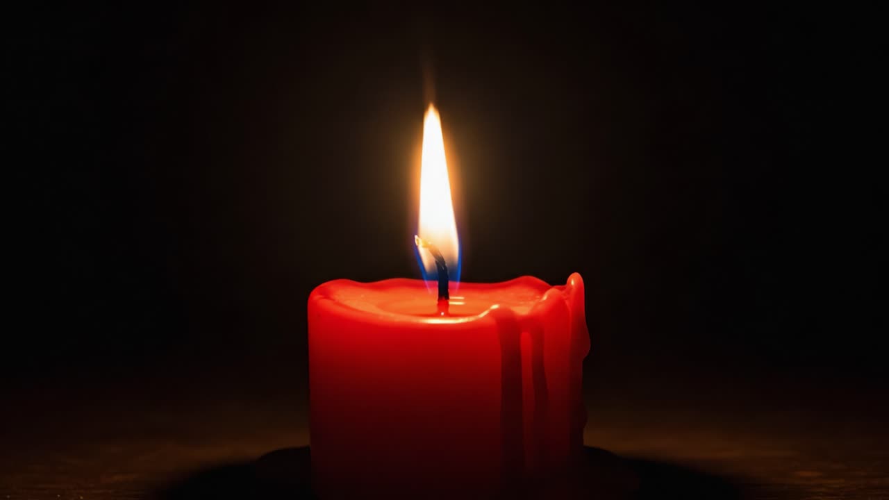 Una candela rossa luminosa illumina uno spazio buio, catturando la bellezza della sua fiamma e della cera che cola in un'atmosfera serena e calma.