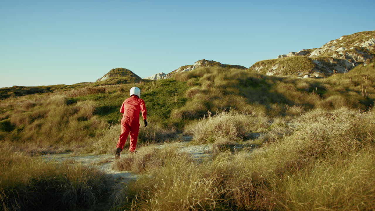 astronauta corre hacia una tierra deshabitada en una colina para pedir ayuda