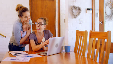 Lesbian-couple-working-on-laptop-in-living-room-4k