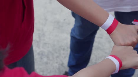 group of young people unite hand together wearing indonesian red and white ribbon on wrist. unity concept