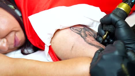 close-up view of a woman getting a realistic wolf tattoo on her upper arm