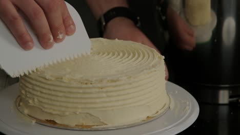 a baker uses a cutout tool to make a spiral design on the top of a sponge cake