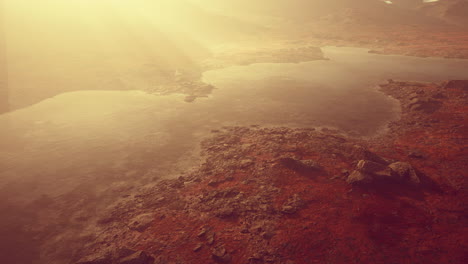 clear river with rocks leads towards mountains lit by sunset