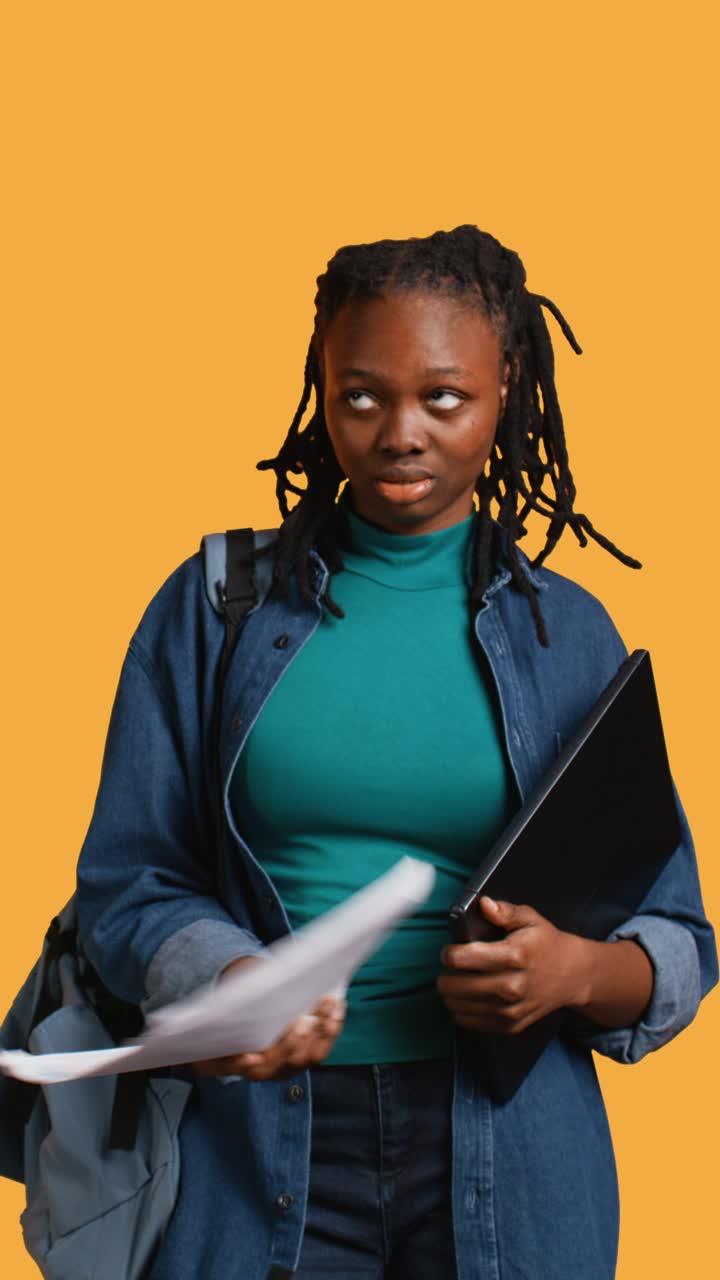 Giovane studentessa afroamericana legge dei documenti e tiene in mano un portatile