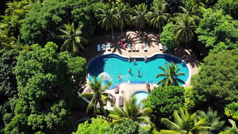 aerial view of a tropical resort swimming pool with people enjoying the water and sun