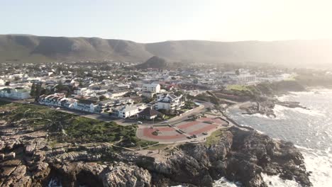 Vista-Aérea-Del-Punto-De-Engranajes-Y-El-Punto-De-Vista-De-Avistamiento-De-Ballenas-Hermanus-Al-Amanecer-En-Hermanus,-Sudáfrica