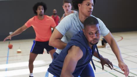 diversos jugadores de baloncesto masculinos driblando la pelota y bloqueando durante el juego en la cancha cubierta, cámara lenta