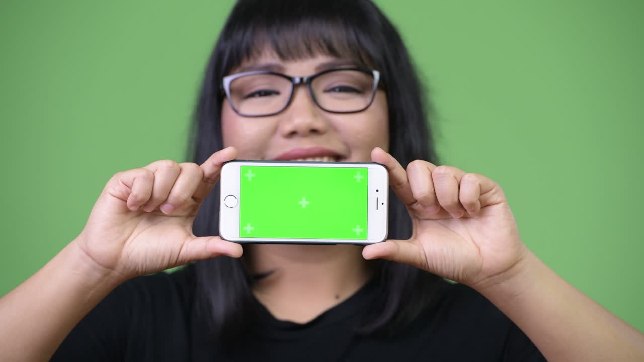 Beautiful Asian businesswoman showing phone while thinking