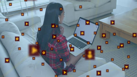 Animation-of-network-of-connections-with-icons-over-biracial-woman-using-laptop-with-copy-space