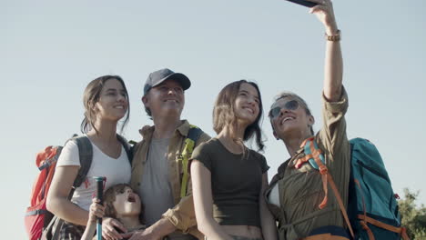 family of backpackers standing on cliff and taking selfie