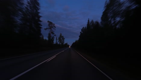 pov: highway curves to oncoming headlights through blue hour forest
