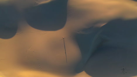 cinematic rising drone shot of man walking alone on sand dunes or the desert