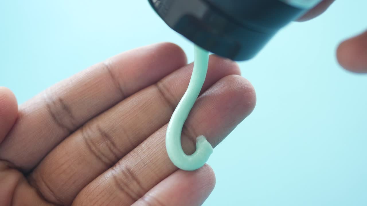 Person Dispensing Green Gel or Lotion onto Hand