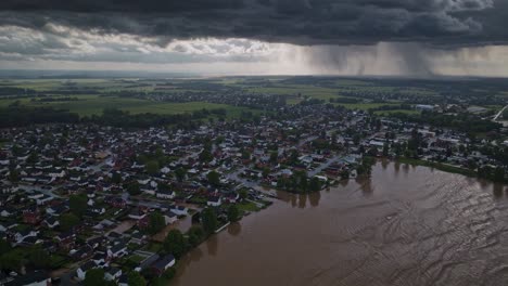 aerial view revealing devastating flood waters surging through residential neighborhood, dark clouds unleashing torrential rain over inundated landscape, highlighting climate change impact