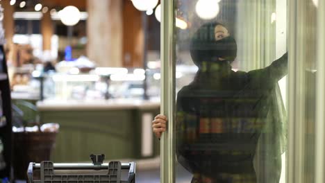 woman in hijab and protective mask takes product from the freezer shelf, slow motion