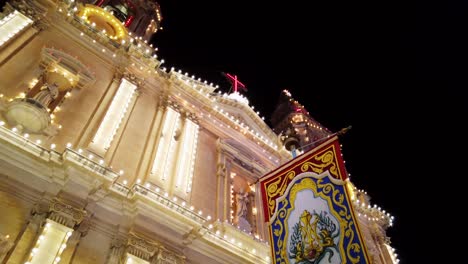 malta, sliema, religious flag hanging in front of a decorated church during a local festa at night