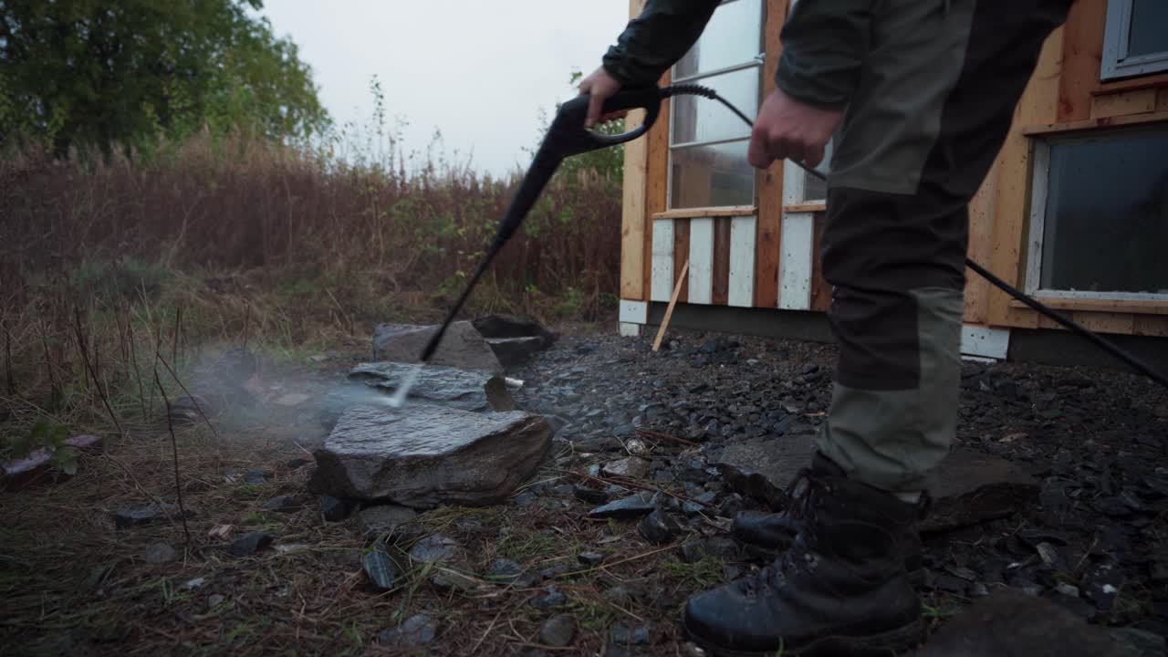 노르웨이 인드레 포센 에서 온실 을 건설 하기 위한 바위 를 청소 하기 위해 압력 세척기 를 사용 하고 있는 사람 - 가까운 사진