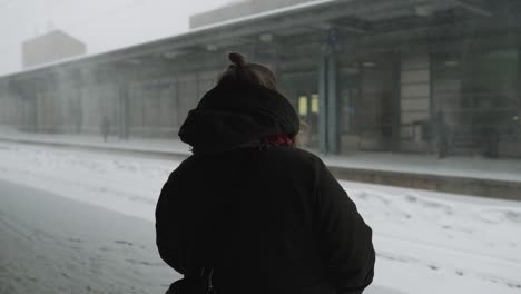 woman waiting for train in snowstorm in helsinki