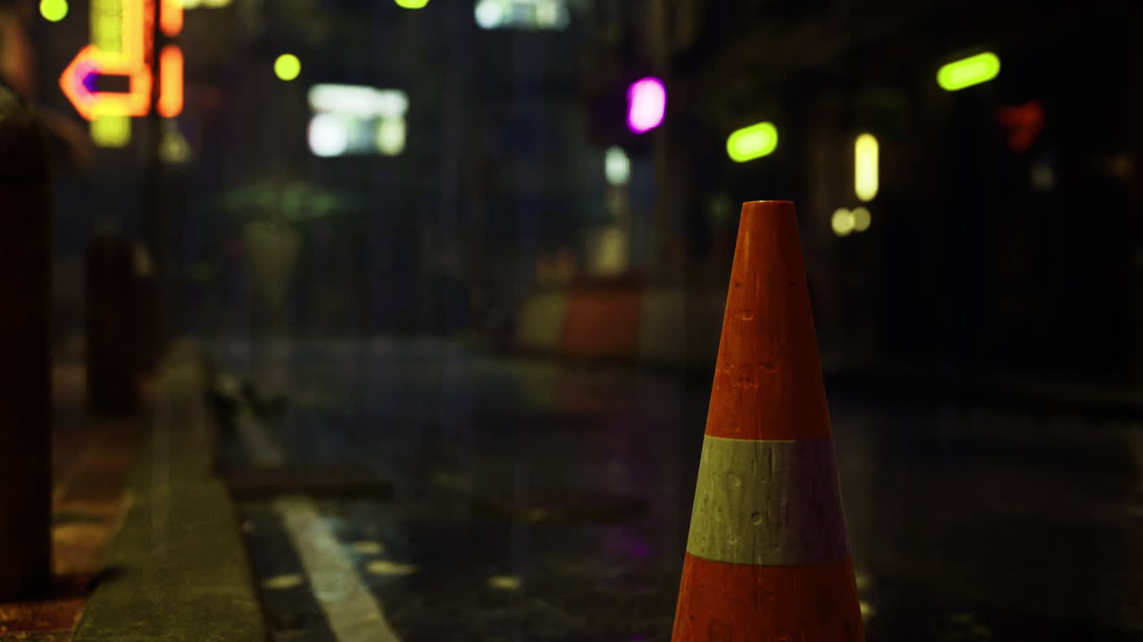 Traffic cone illuminated by neon lights in a rainy urban setting at night