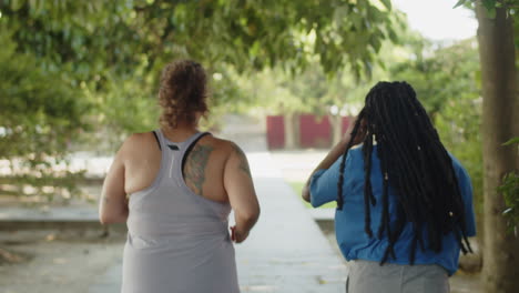 Back-view-of-fat-multiethnic-women-running-along-path-in-park