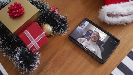 Smiling-caucasian-woman-drinking-coffee-on-christmas-video-call-on-tablet