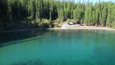 Vista-Aislada-De-Un-Hombre-Remando-De-Pie-En-Aguas-Tranquilas-Azules-En-El-Lago-Ashley-En-Montana,-Estados-Unidos