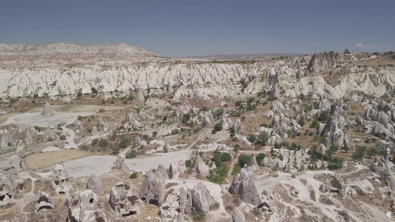 Göreme, Kapadokya'daki geleneksel mağara evlerinin üzerinde 4K 10-bit havadan ileri doğru drone çekimi. Güneşli bir yaz gününde, antik kaya konutları ve eşsiz mimarinin açık gökyüzü altında panoramik görüntüleri.