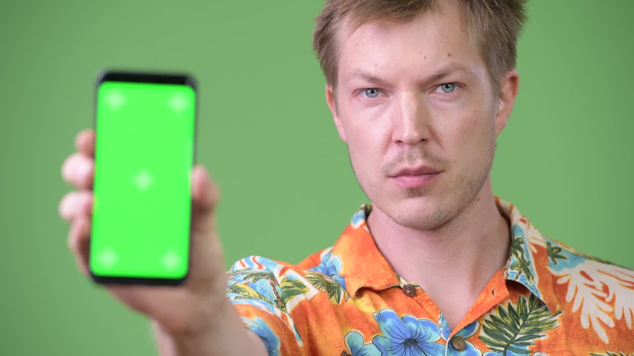Young happy handsome tourist man smiling while showing phone