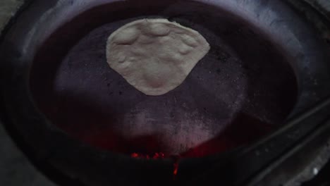 cooking indian garlic naan bread in charcoal oven. close-up