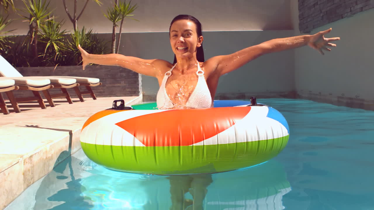 una mujer bonita emergiendo de bajo el agua en un anillo de goma en la piscina