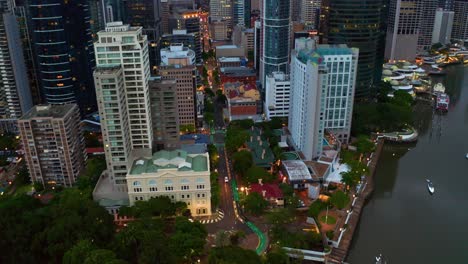 gardens point boat harbour with view of apartment and hotel buildings along edward street in brisbane, australia at dusk