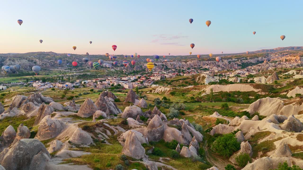Hot air balloons over rock formations in Cappadocia at sunrise, calm scenery
