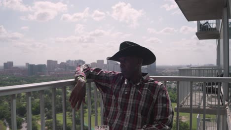 Afroamerikanischer-Mann-Mit-Cowboyhut-Sitzt-Auf-Dem-Balkon-Und-Genießt-Die-Friedliche-Zeit
