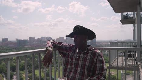 african american male with cowboy hat sitting on balcony enjoying peaceful time